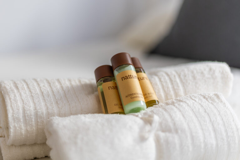 Botellas de productos de baño sobre toallas blancas. Etiquetas marrones, ambiente elegante y suave.